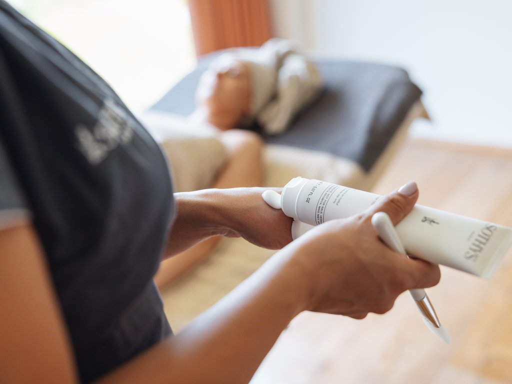 Trentino: Hotel am See mit Pool und Spa Kosmetikerin trägt Creme auf die Hand eines Kunden im Spa auf