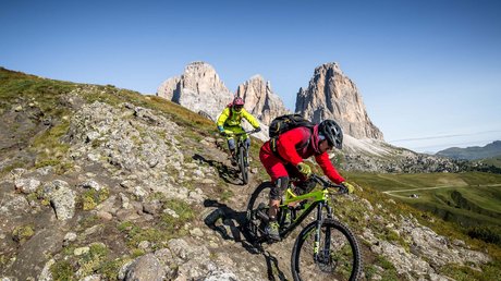 Picture gallery Two mountain bikers on a trail with the Dolomites mountains in the background