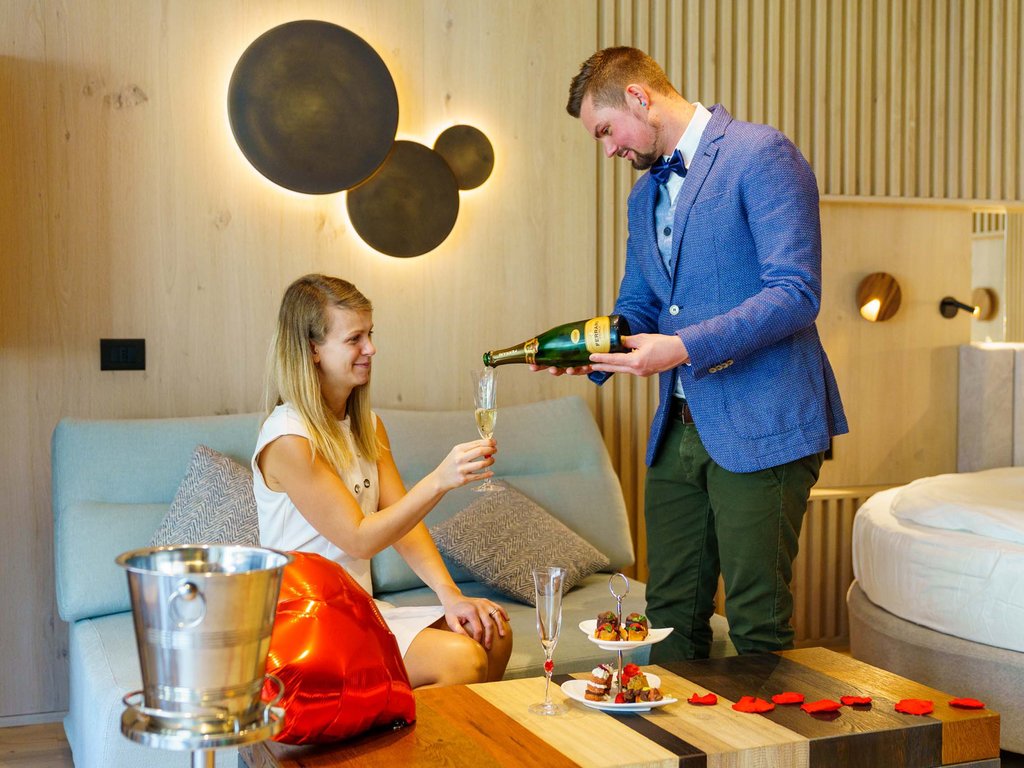 Sulla pista ciclabile, da Moena alla vostra oasi romantica Coppia che brinda con champagne in un ambiente elegante con decorazioni romantiche