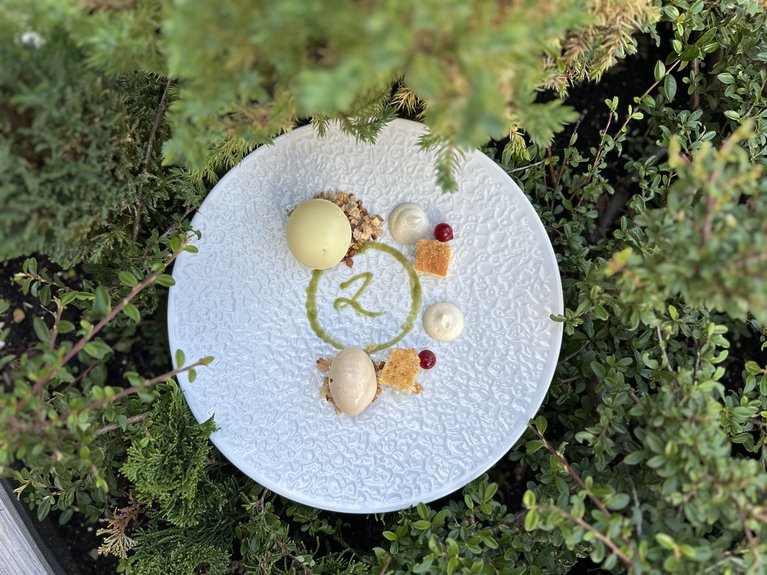 Restaurant Mirage mit Dolomiten-Blick im Fassatal Gourmet-Dessert mit Eis und Dekoration auf weißem Teller