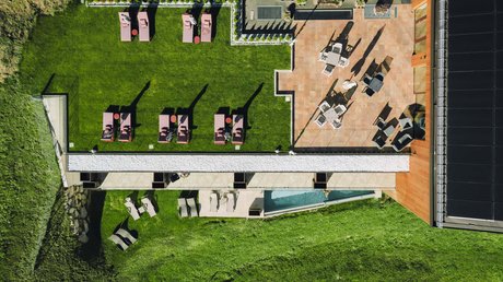 Picture gallery Aerial view of a garden with lounge chairs, pool, and terrace with tables