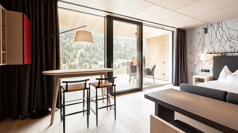 Moena: Unterkunft für Ihren Traumurlaub. Hotel Latemar! Innenraum eines modernen Zimmers mit Tisch, Stühlen und Balkon mit Bergblick