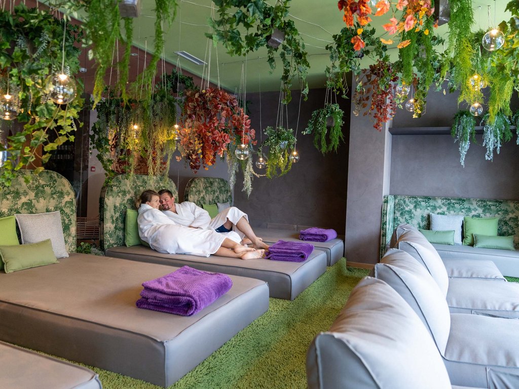 Soraga di Fassa: Urlaub in und mit der Natur Paar in Bademänteln entspannt auf Liegen in Spa mit hängenden grünen Pflanzen