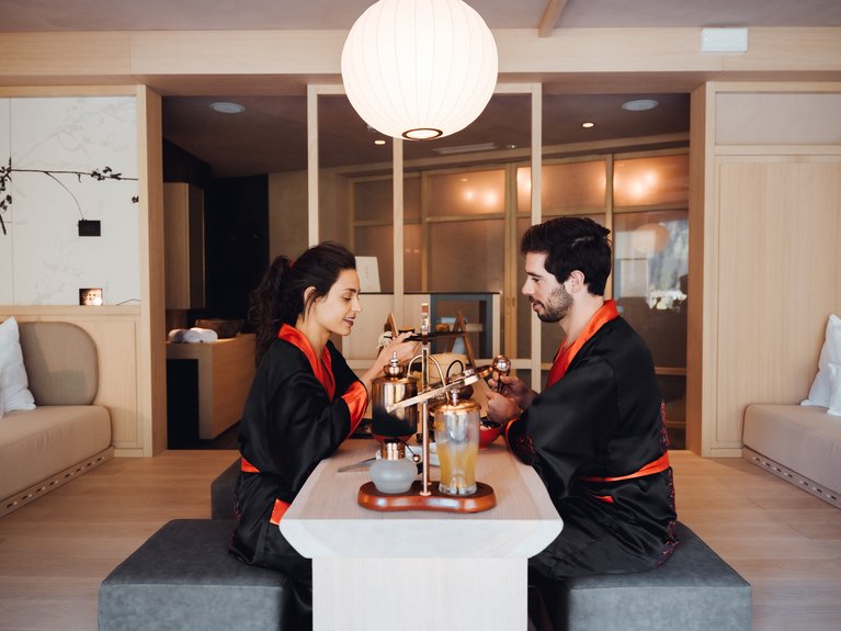 Urlaub im Fassatal: Erholung pur Paar in schwarzem und rotem Kimono sitzt an einem Tisch in einem minimalistischen Zimmer