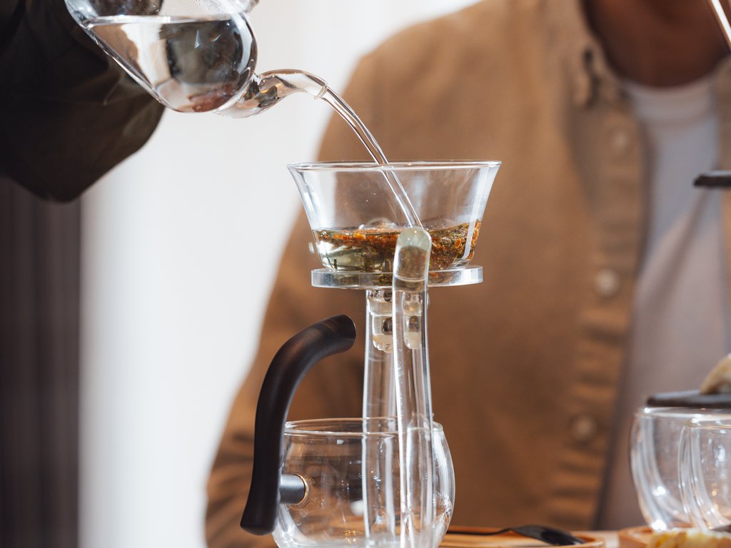 Sulla pista ciclabile, da Moena alla vostra oasi romantica Una persona versa acqua da una teiera in un infusore di tè su un tavolo