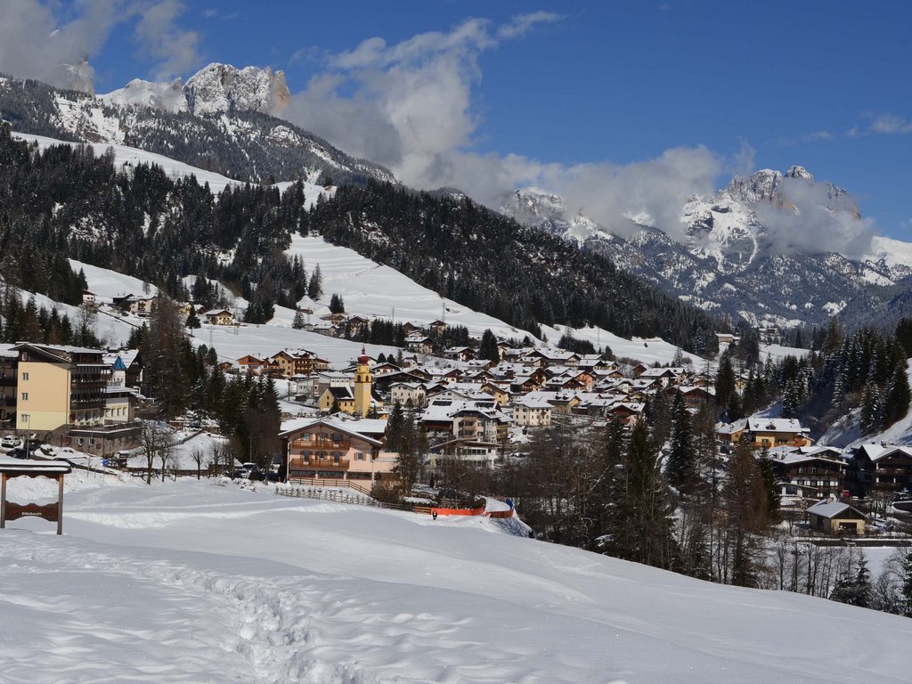 Hotel Latemar con vista sulle Dolomiti Paesino innevato ai piedi delle montagne Dolomiti con cielo azzurro.