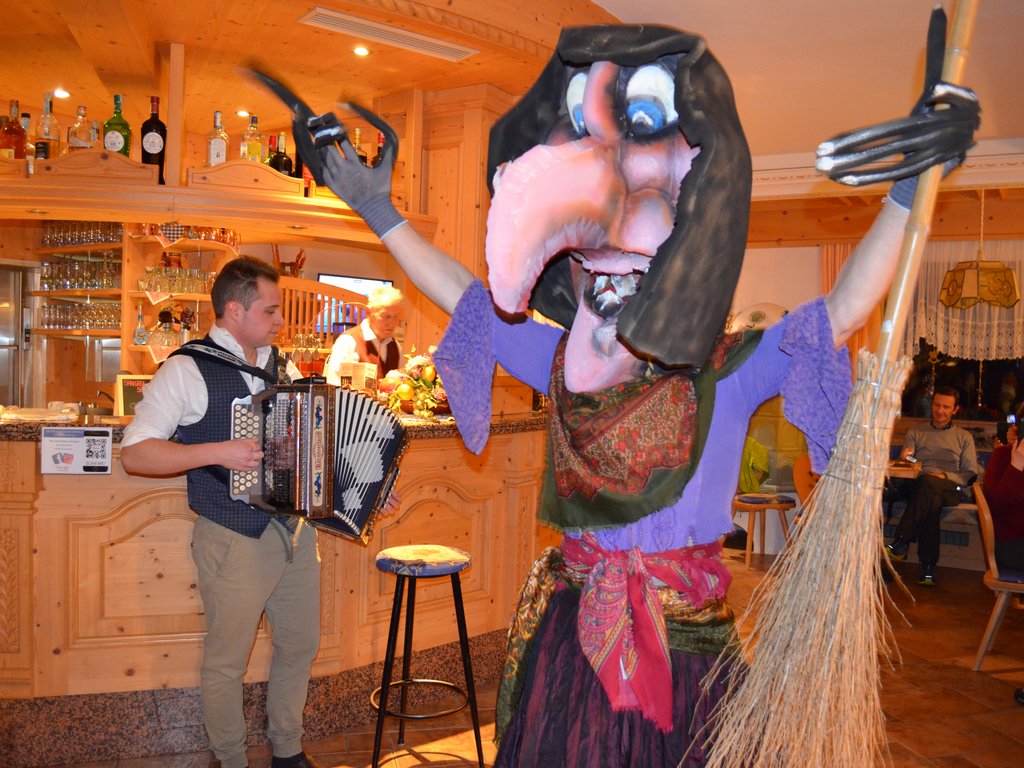 Hotel a Soraga: passione di famiglia Persona con costume di strega e scopa, musicista suona fisarmonica in bar