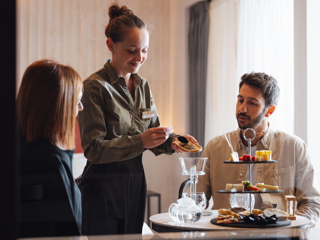 Sulla pista ciclabile, da Moena alla vostra oasi romantica Coppia a tavola con cameriera che mostra una confezione di tè o spezie