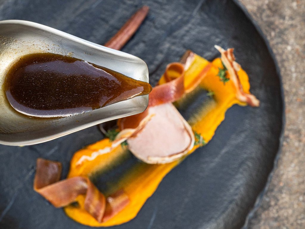 Per buongustai: l’hotel ideale vicino a Moena Salsa versata su piatto con purea arancione e carne decorata