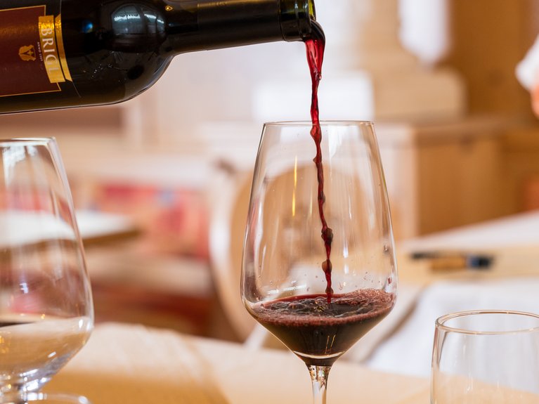 Ristorante a Soraga di Fassa: Mirage con #latermarview Vino rosso versato in un calice su un tavolo apparecchiato.