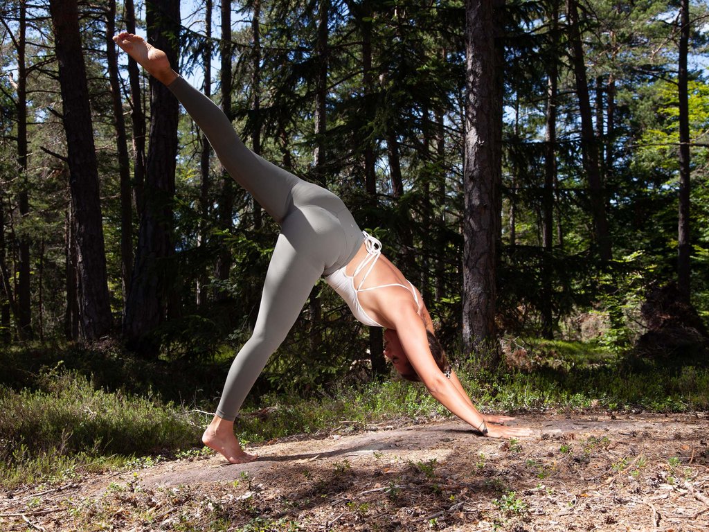 Fassatal Skigebiet Pistenplan Frau macht Yoga im Wald mit angehobenem Bein
