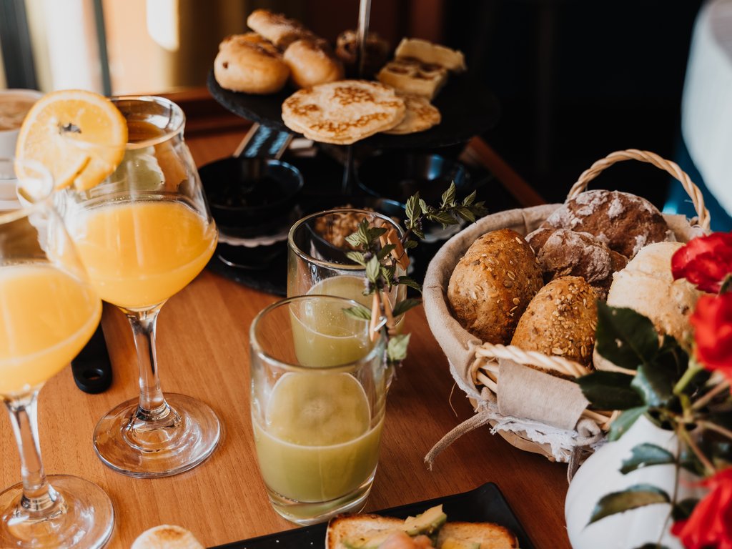 Soraga bei Südtirol im Trentino Frühstück mit Toast, Säften, Brot, Aufschnitt und roten Blumen auf Holztisch