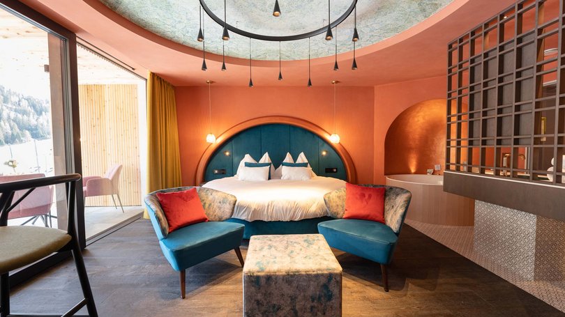 Moena: Unterkunft für Ihren Traumurlaub. Hotel Latemar! Modernes Schlafzimmer mit blauen Sesseln, rundem Bett und großem Fenster