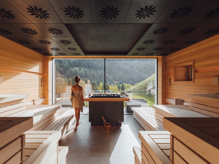 Hotel Latemar mit Dolomitenblick Frau mit Handtuch in moderner Sauna mit Panoramablick auf die Berge