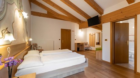 Picture gallery Hotel bedroom with double bed, wooden beam ceiling, and an open bathroom door