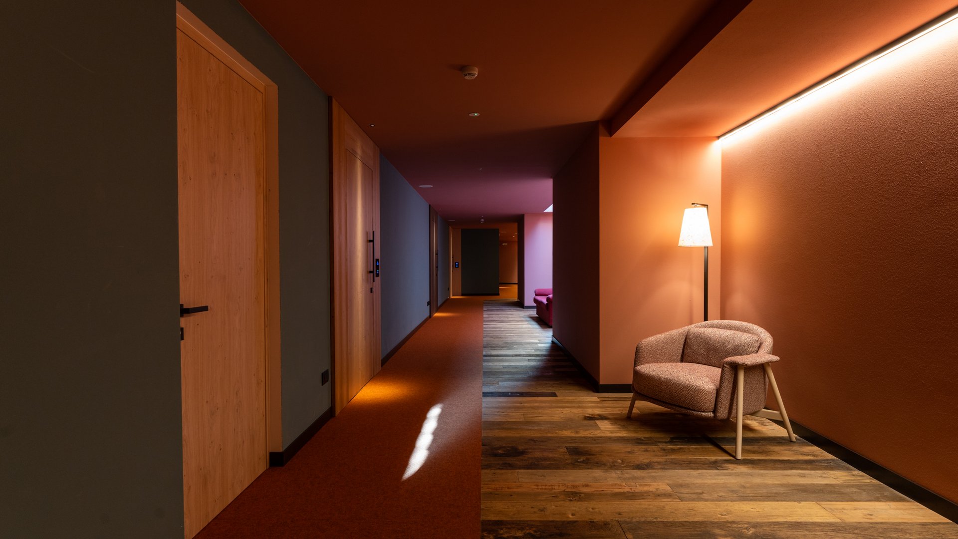 Modern hallway with armchair, warm lighting, and wooden floor