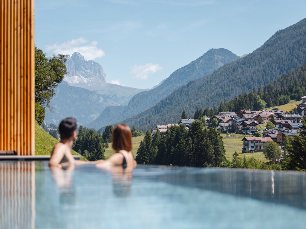 Trentino: Hotel am See mit Pool und Spa Paar im Infinity-Pool mit Blick auf Berge und Dorf