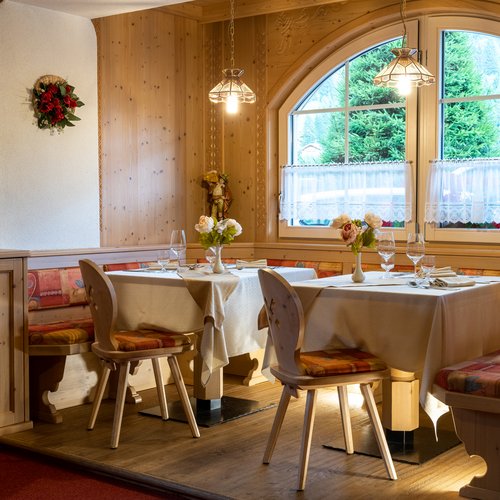 Restaurant Mirage mit Dolomiten-Blick im Fassatal Eleganter Essbereich aus Holz mit gedeckten Tischen und Bergblick
