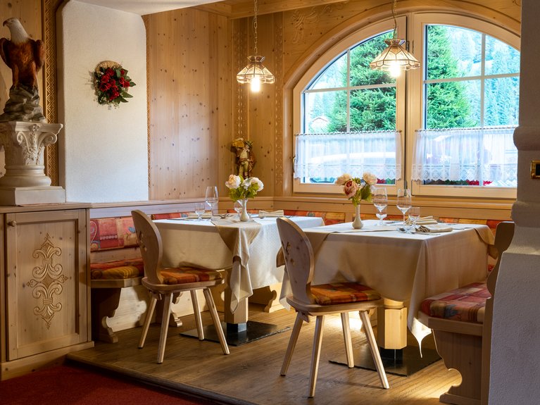 Ristorante a Soraga di Fassa: Mirage con #latermarview Sala da pranzo elegante in legno con tavoli apparecchiati e vista sulle montagne