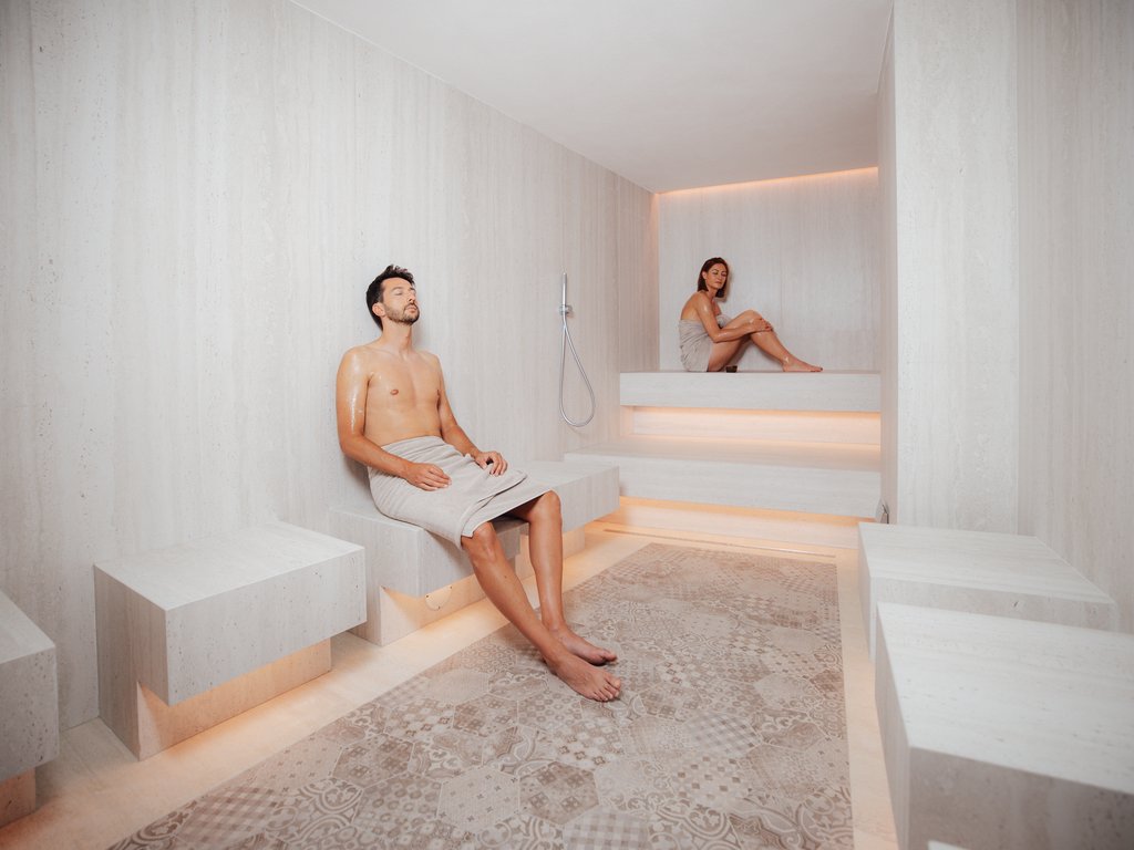 Al Latemar, dopo le passeggiate: relax nella Spa Oniro Uomo e donna rilassati in sauna moderna con pareti e pavimento chiari