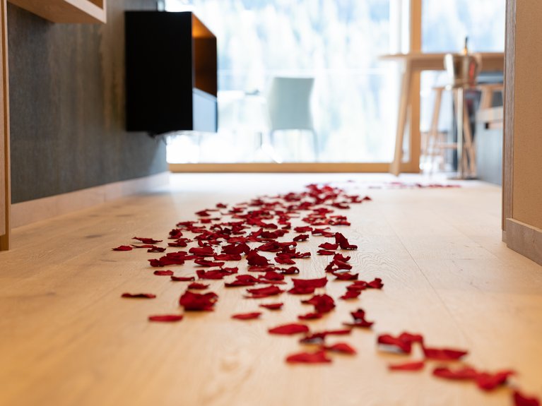 Hotel Latemar con vista sulle Dolomiti Petali di rosa rossi sparsi sul pavimento in legno di una stanza luminosa