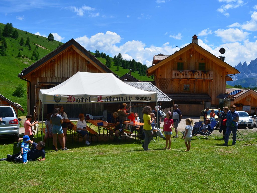 Per buongustai: l’hotel ideale vicino a Moena Persone riunite sotto una tenda bianca davanti a baite in montagna