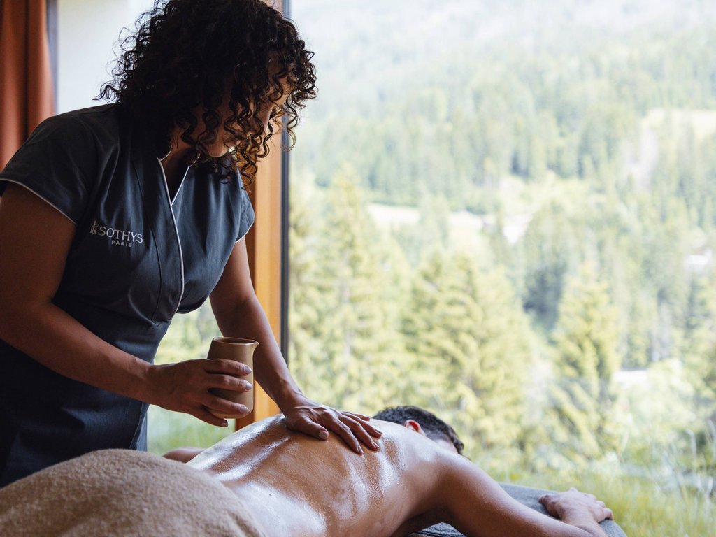 Trentino: Hotel am See mit Pool und Spa Masseurin trägt Öl auf den Rücken eines Mannes mit Bergblick auf