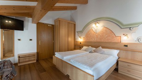 Meteo, Moena, Soraga, Latemar: tutto nella nostra gallery Camera da letto con letto matrimoniale, mobili in legno e soffitto con travi a vista