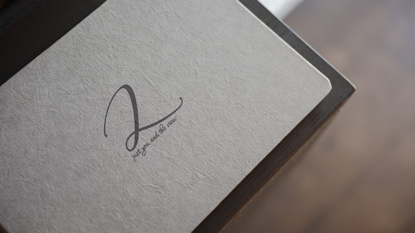 Moena: Unterkunft für Ihren Traumurlaub. Hotel Latemar! Weißes Notizbuch mit eleganter Schrift auf dunklem Tisch