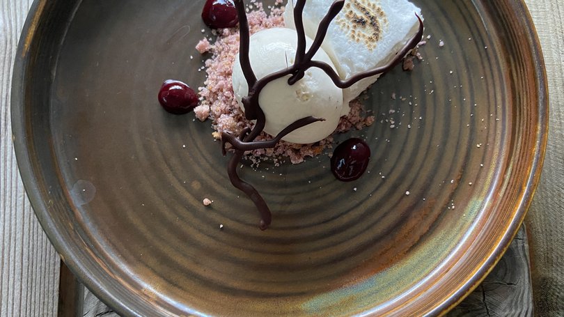 Moena, alberghi da sogno, panorama? C’è l’Hotel Latemar! Dessert con marshmallow tostato, crema bianca, cioccolato e salsa rossa su piatto marrone