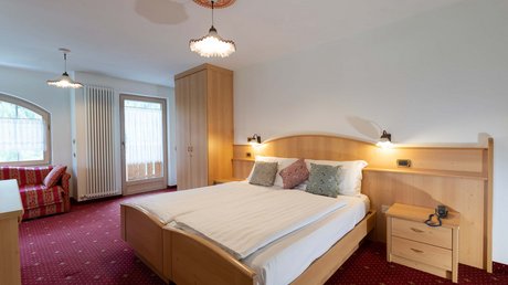 Meteo, Moena, Soraga, Latemar: tutto nella nostra gallery Camera da letto con letto matrimoniale, armadio, divano rosso e moquette rossa