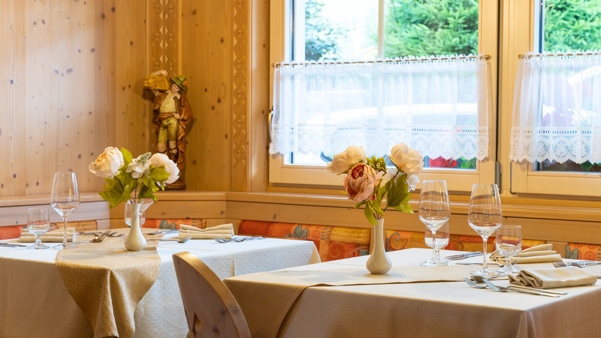 Soraga bei Südtirol im Trentino Eingedeckte Tische mit Blumen in einem gemütlichen Restaurant mit Holzwänden