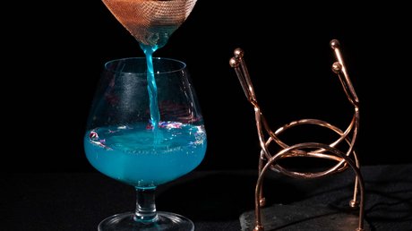 Picture gallery Blue liquid strained into a cocktail glass with black background