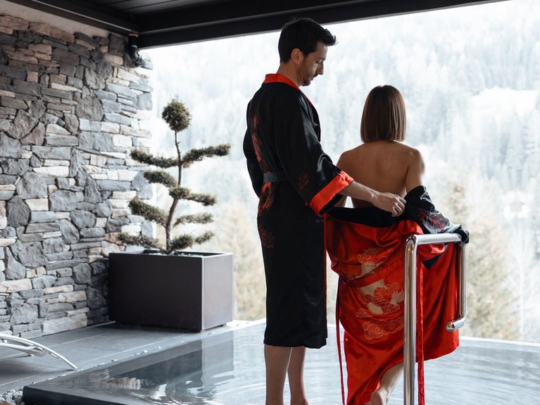 Urlaub im Fassatal: Erholung pur Paar mit Kimonos betritt Pool mit Bergblick
