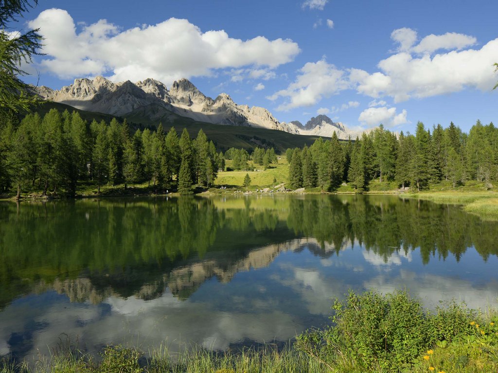 Val di Fassa: Hotel Latemar Ruhiger Alpensee mit Spiegelung von Bäumen und sonnigen Bergen