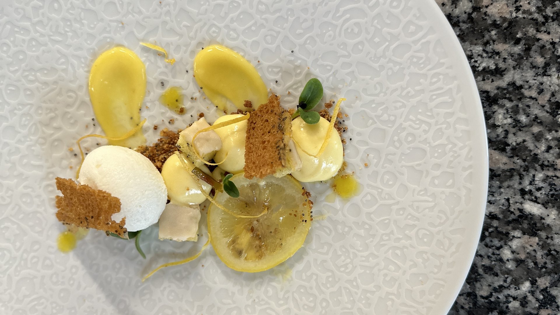 Restaurant Mirage mit Dolomiten-Blick im Fassatal Gourmet-Dessert mit Zitronencreme, Baiser und knusprigen Dekorationen auf weißem Teller