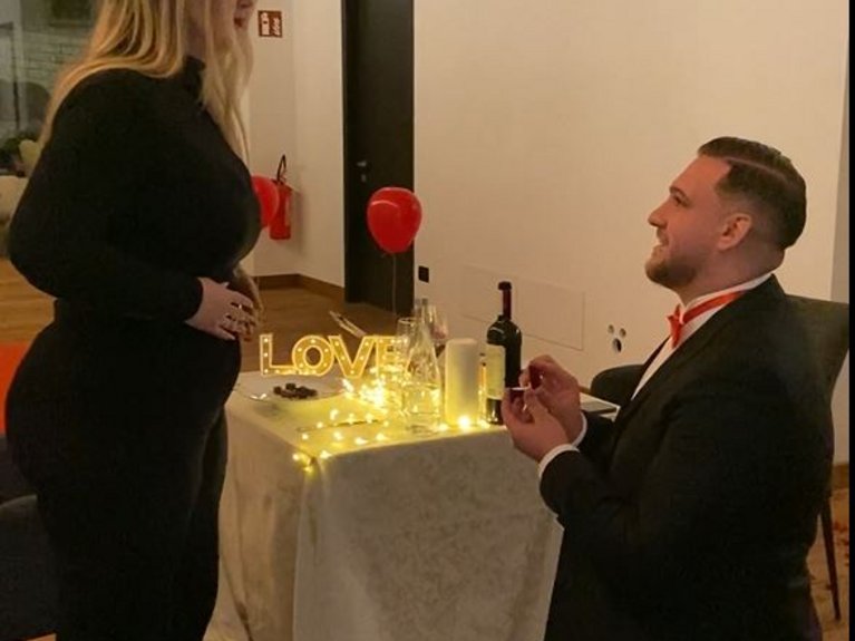 Sulla pista ciclabile, da Moena alla vostra oasi romantica Uomo in ginocchio fa proposta di matrimonio a donna davanti a tavolo decorato