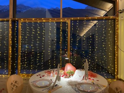 Hikes from Moena and much more: our programme Romantic dining table with lights and red decorations by window with mountain view