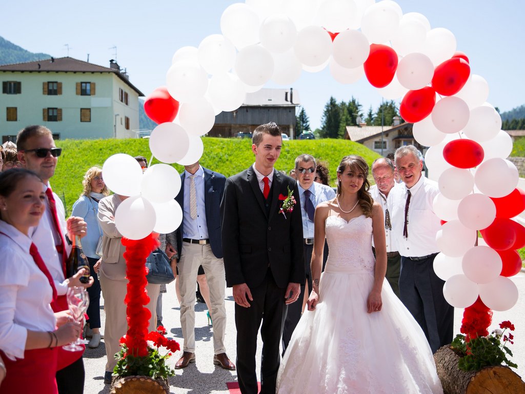 On the webcam Latemar is lovely, in real life it’s a dream! Bride and groom with guests under red and white balloon arch outdoors