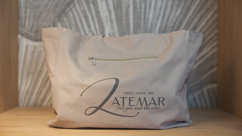 Moena: Unterkunft für Ihren Traumurlaub. Hotel Latemar! Beige Tasche mit Latemar-Logo auf einem Holzregal