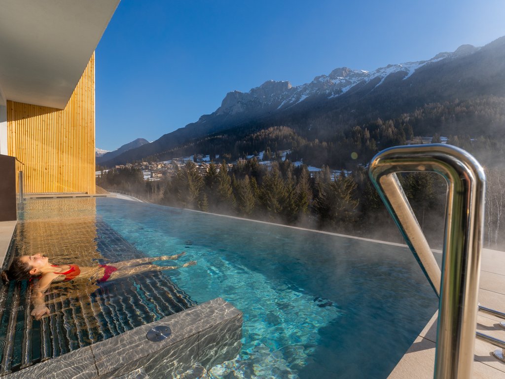 Barrierefreies Hotel im Val di Fassa: das Latemar Frau entspannt im beheizten Pool mit Blick auf verschneite Berge