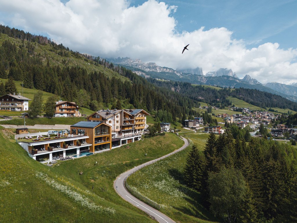 Hotel Latemar mit Dolomitenblick Hotel am Hügel mit gewundener Straße und Bergen im Hintergrund