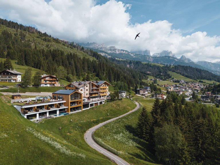 Hotel Latemar mit Dolomitenblick Hotel am Hügel mit gewundener Straße und Bergen im Hintergrund