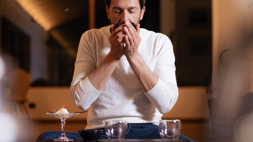 Val di Fassa: wandern, biken, erleben Mann trinkt aus einer Tasse, sitzt an einem niedrigen Tisch in gemütlicher Umgebung