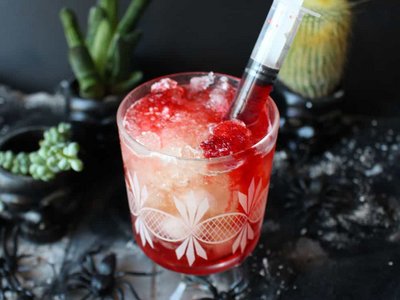 A Soraga il meteo è sempre ottimo per un Day Spa! Cocktail rosso con ghiaccio in un bicchiere decorato, con una siringa inserita