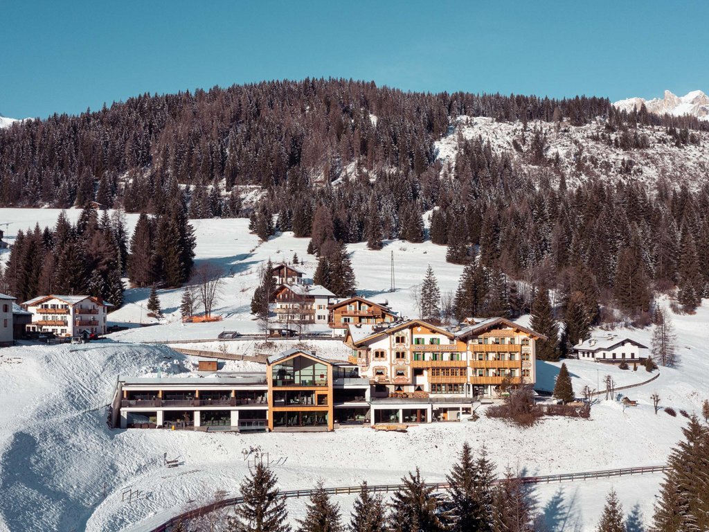 Val di Fassa: l’Hotel Latemar si trova qui Hotel invernale tra alberi innevati e montagne soleggiate