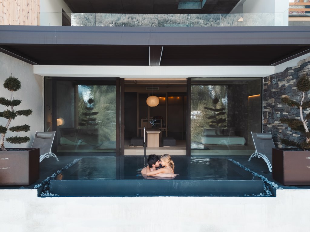 Urlaub im Fassatal: Erholung pur Paar umarmt sich in einem privaten Pool in einem modernen Wellnessbereich