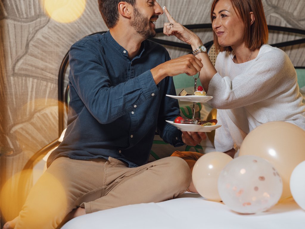 Sulla pista ciclabile, da Moena alla vostra oasi romantica Coppia che si diverte a scambiarsi dolci su un letto decorato con palloncini.