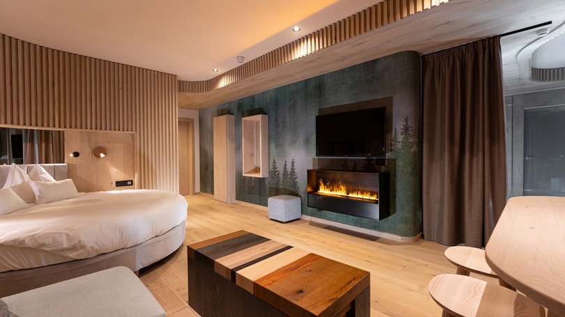 Moena: Unterkunft für Ihren Traumurlaub. Hotel Latemar! Modernes Hotelzimmer mit rundem Bett, elektrischem Kamin und Holzmöbeln