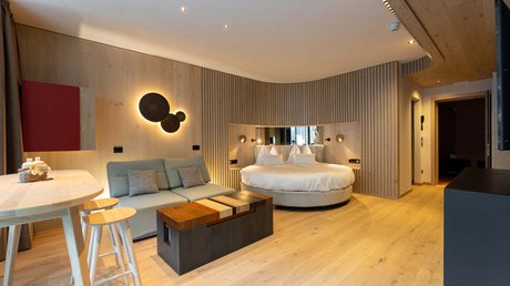 Meteo, Moena, Soraga, Latemar: tutto nella nostra gallery Camera moderna con letto rotondo, divano azzurro e arredo in legno chiaro.